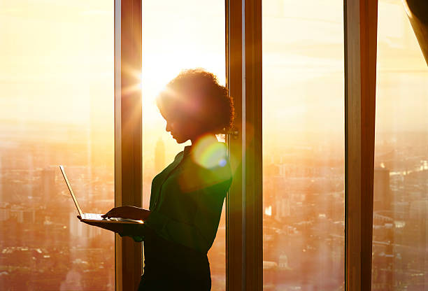 Woman working on laptop by a sunny window