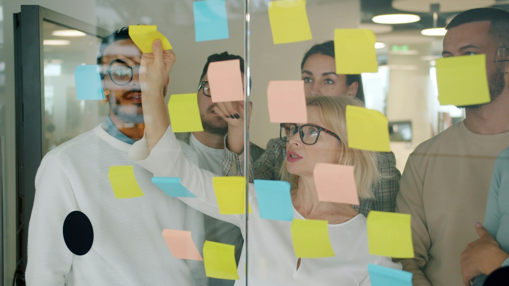 Team brainstorming with sticky notes on a glass wall